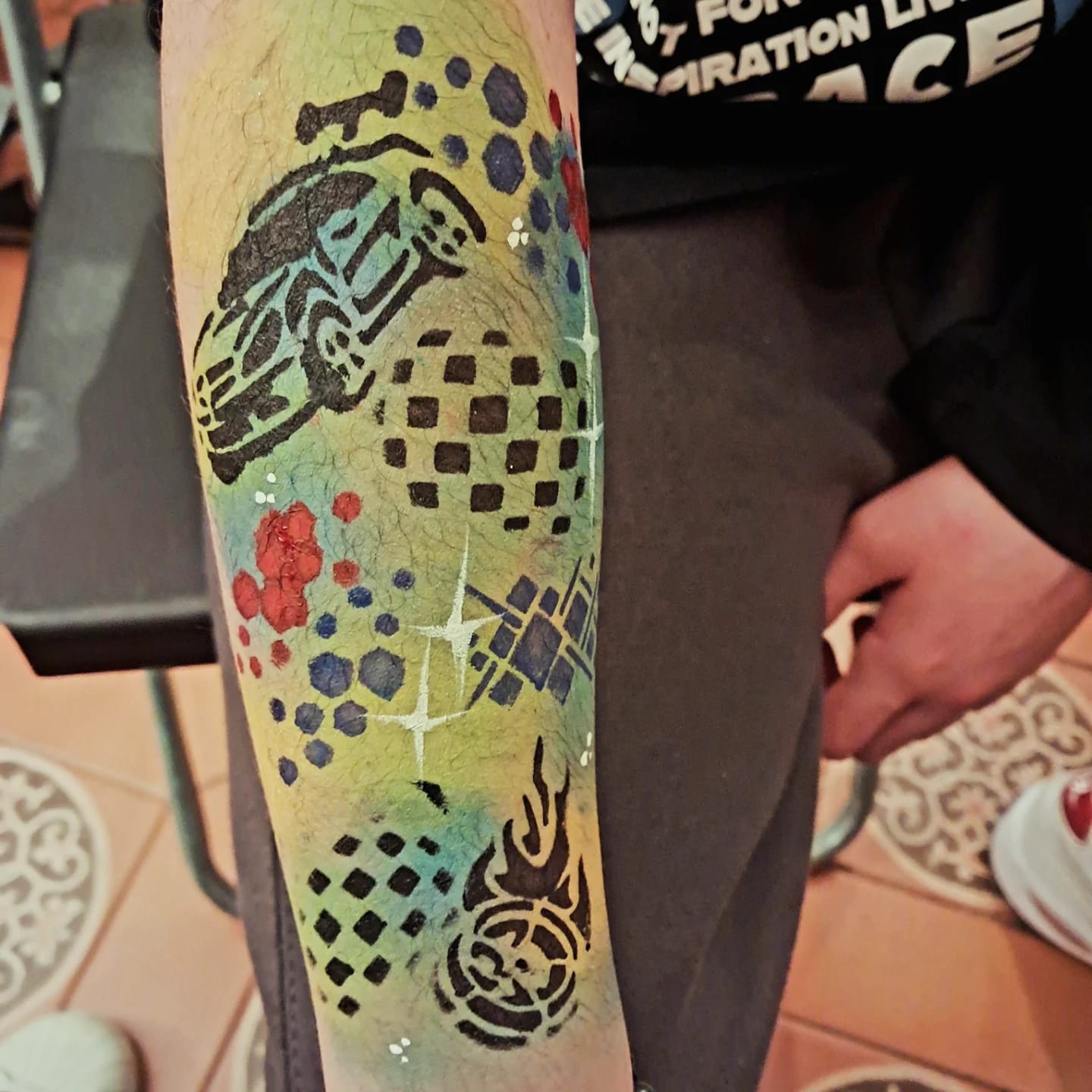 Tatuaje temporal en el brazo con diseño de coche de carreras y purpurina
